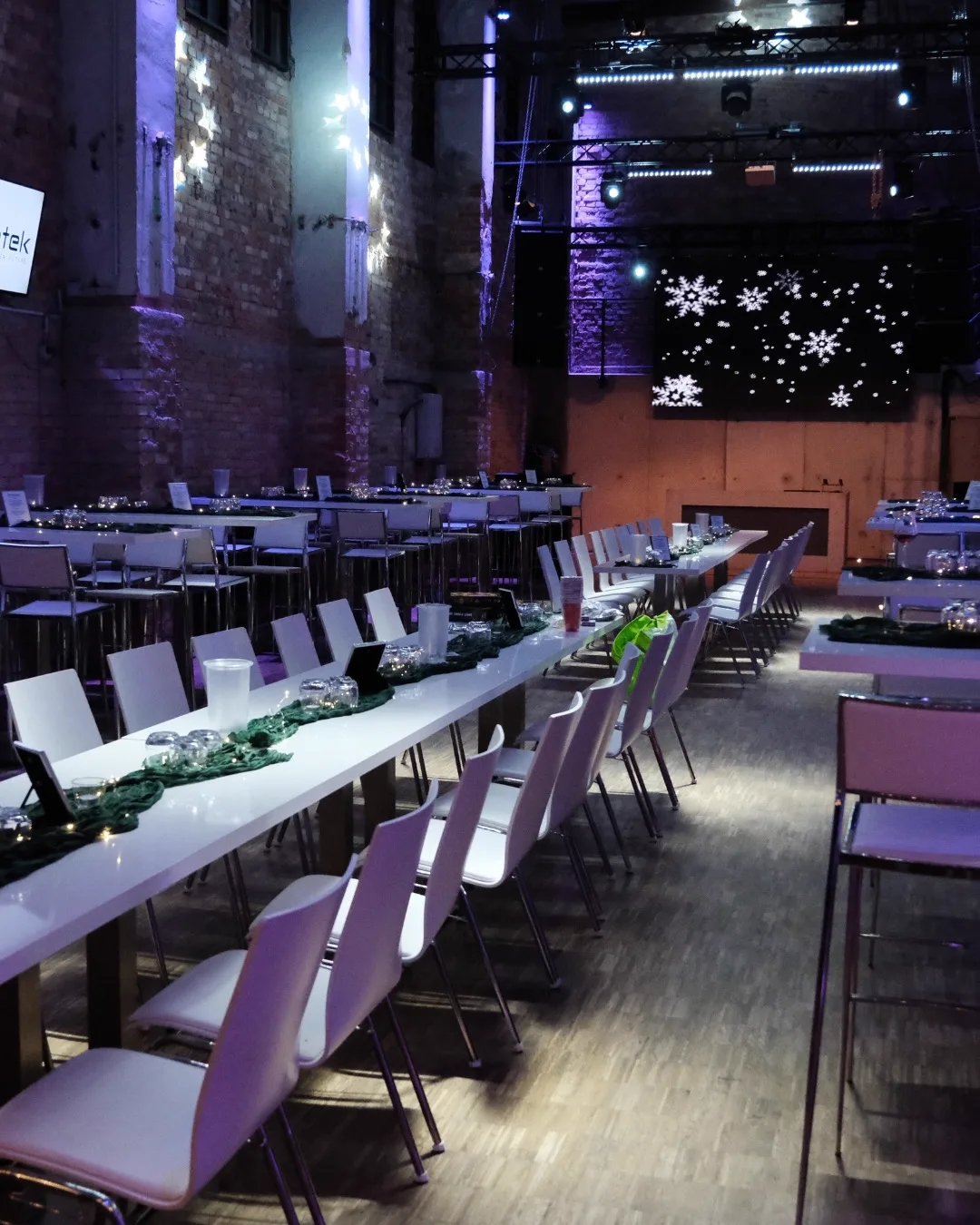 Weihnachtlich beleuchtete Halle des Alten Pumpenhauses mit langen Tafeln und Schneeflocken-Wand